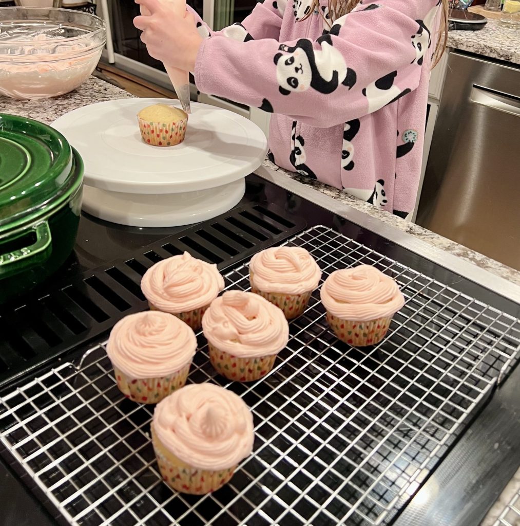 Hands piping frosting onto cupcakes during a birthday baking activity