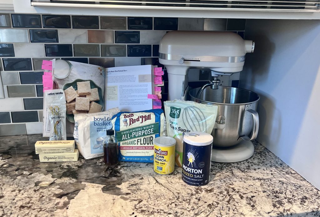 Open cookbook page from Sally’s Baking 101 with ingredients laid out for vanilla bean shortbread bars.