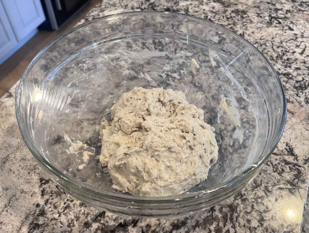 Sticky rosemary garlic bread dough in mixing bowl before shaping and baking