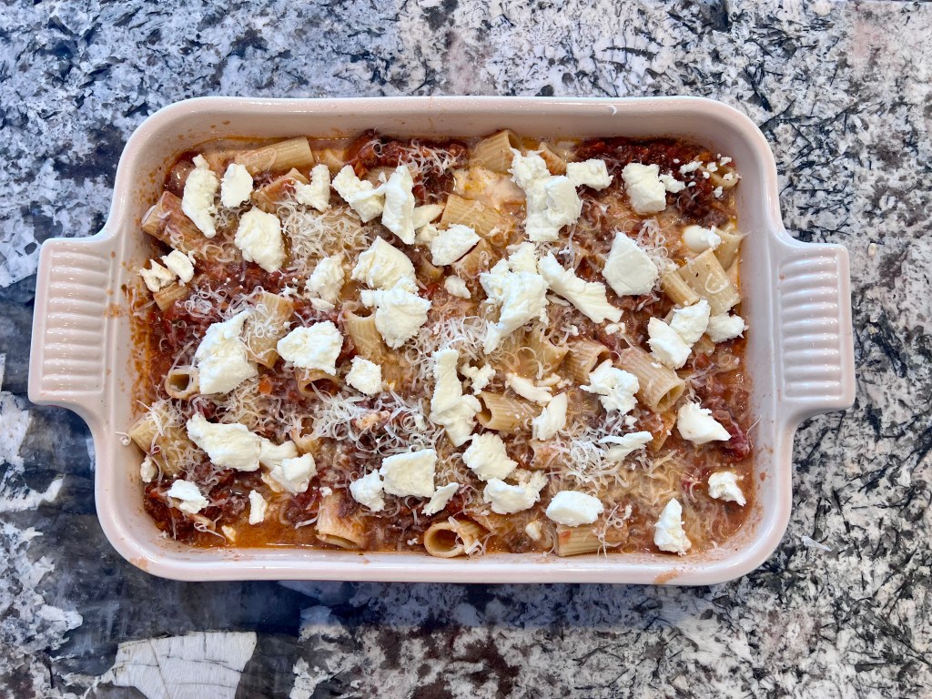 Assembled baked rigatoni with beef ragu in a baking dish before refrigerating overnight