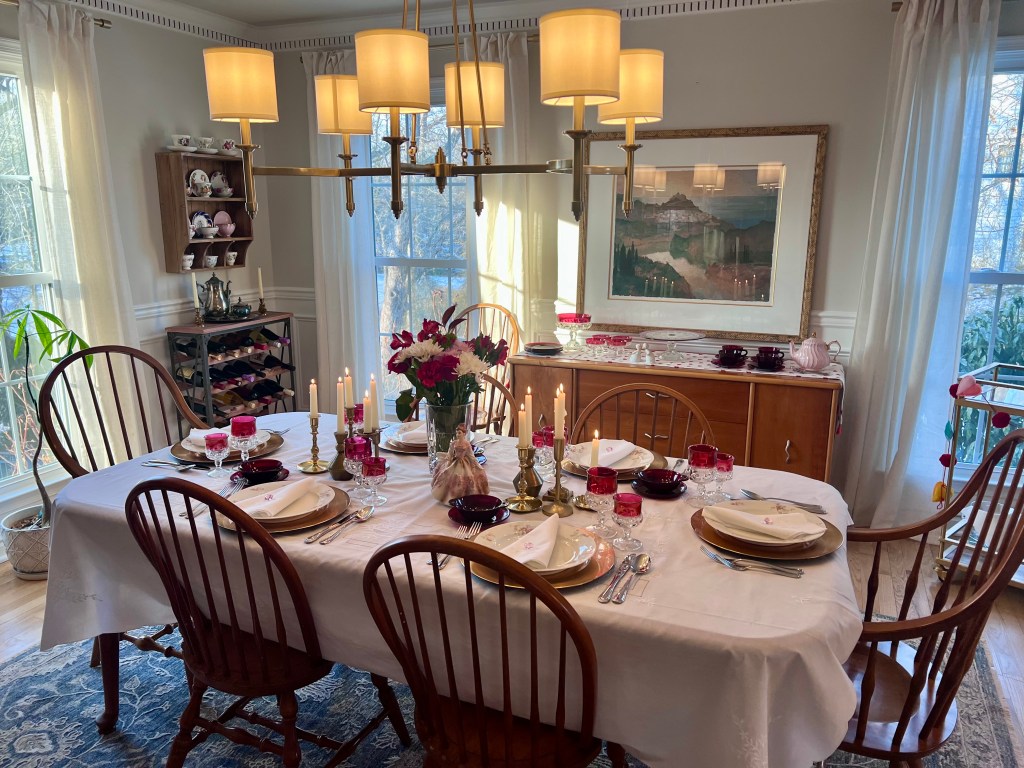 Dining room set for Valentine’s Day with antique Limoges dinner plates, ruby Indiana Glass punch bowl and glasses, vintage figurines, and white heirloom linens.