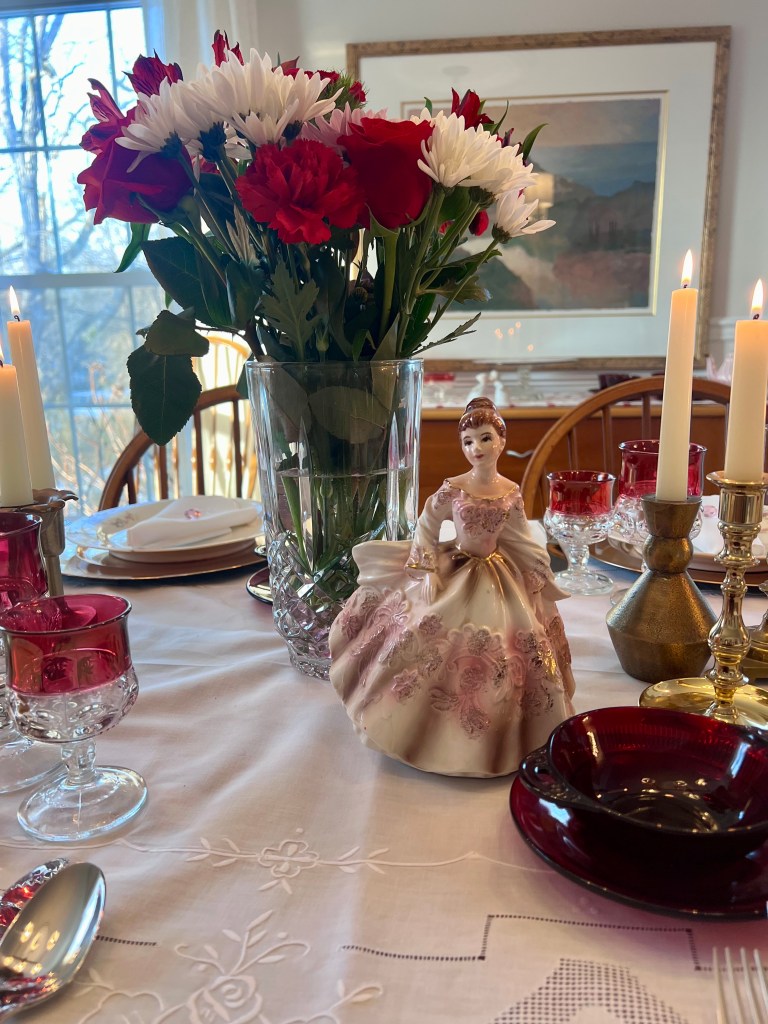 Vintage porcelain Cinderella planter displayed on a Valentine’s Day dining table among heirloom china and ruby glassware.