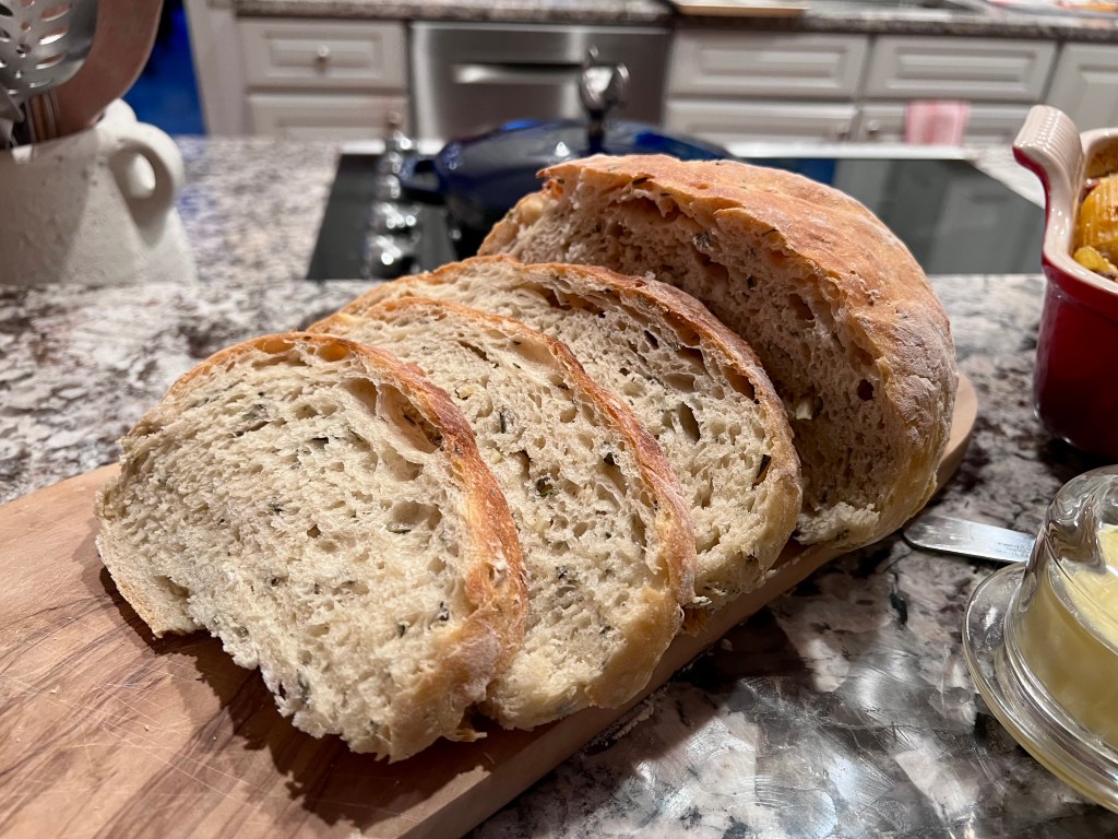 Homemade garlic rosemary bread sliced on a wooden board.