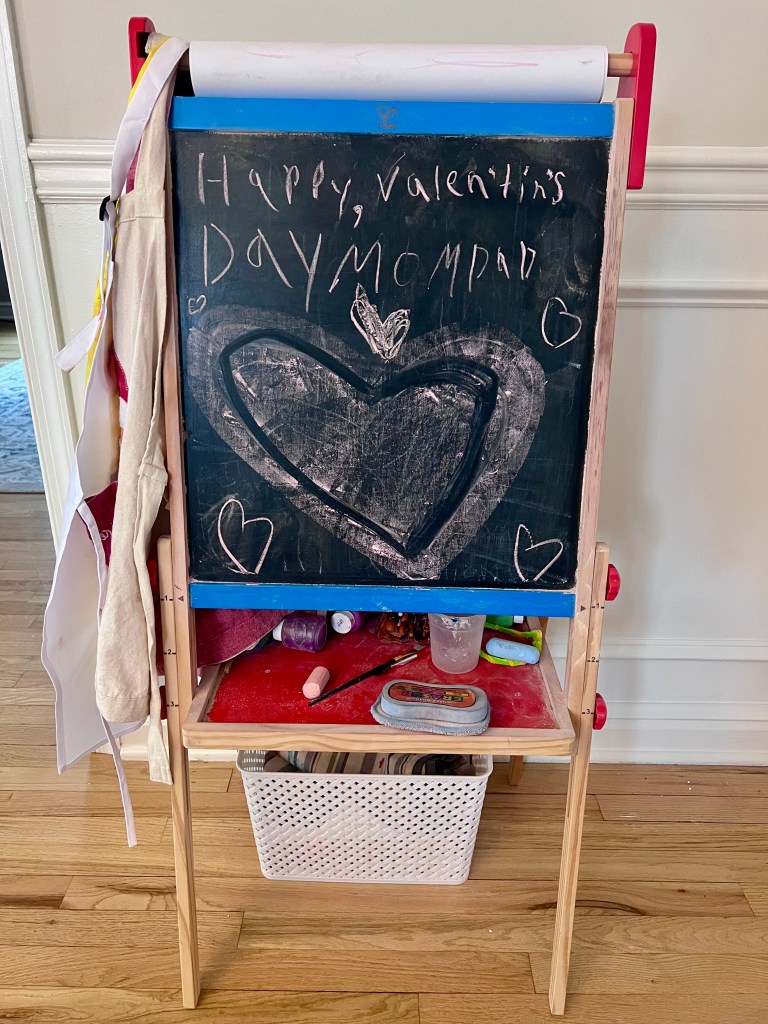 Hand-drawn “Happy Valentine’s Day” sign on a child’s chalkboard displayed in the dining room.