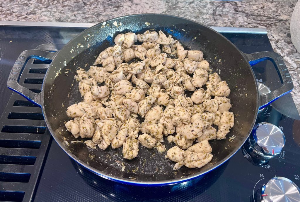 Cooked Italian seasoned chicken bites in a skillet, lightly browned and cooked with dried herbs.