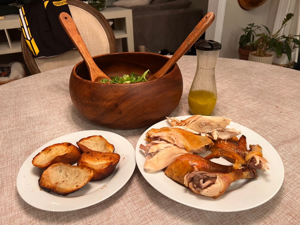 Carved garlic and rosemary roast chicken served with toasted baguette slices and a simple green salad