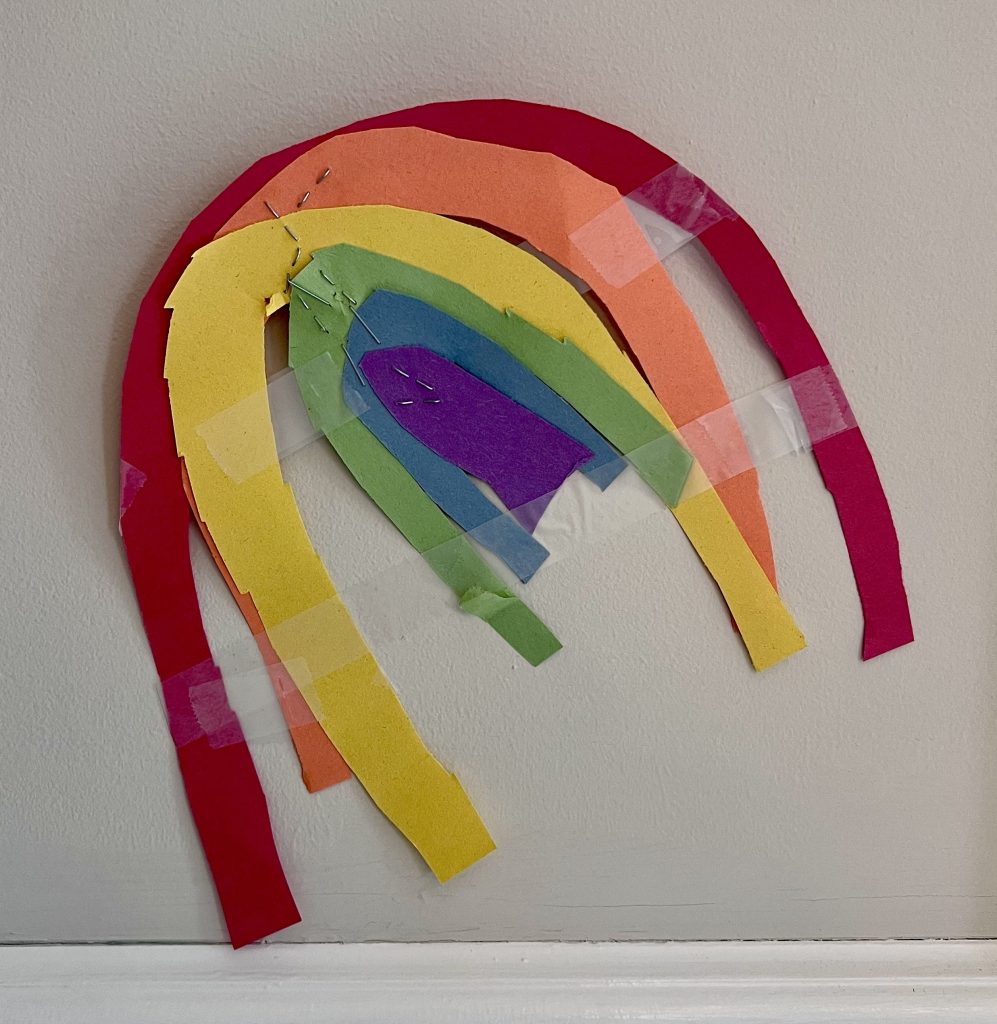 Kids handmade paper rainbow decoration taped to the wall for St. Patrick’s Day