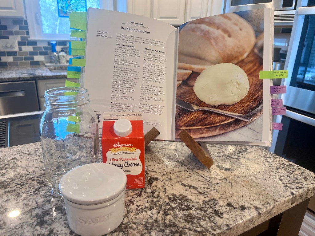 Stay At Home Chef cookbook open to the homemade butter recipe with heavy cream and salt on the kitchen counter