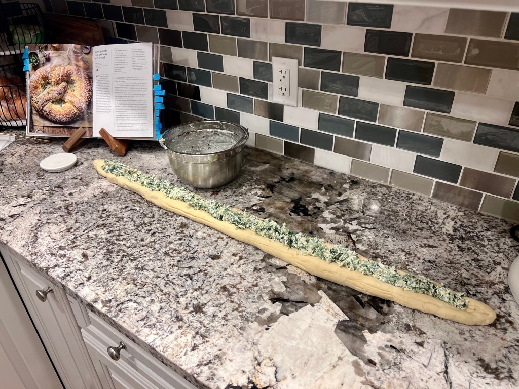 Soft pretzel dough rolled out and stuffed with spinach artichoke filling before shaping and baking