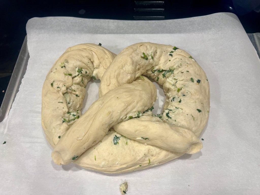 Stuffed spinach artichoke pretzel dough after baking soda wash on parchment-lined baking sheet before baking