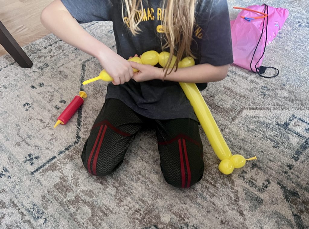 Balloon being twisted into sections while making a balloon animal during kids craft activity