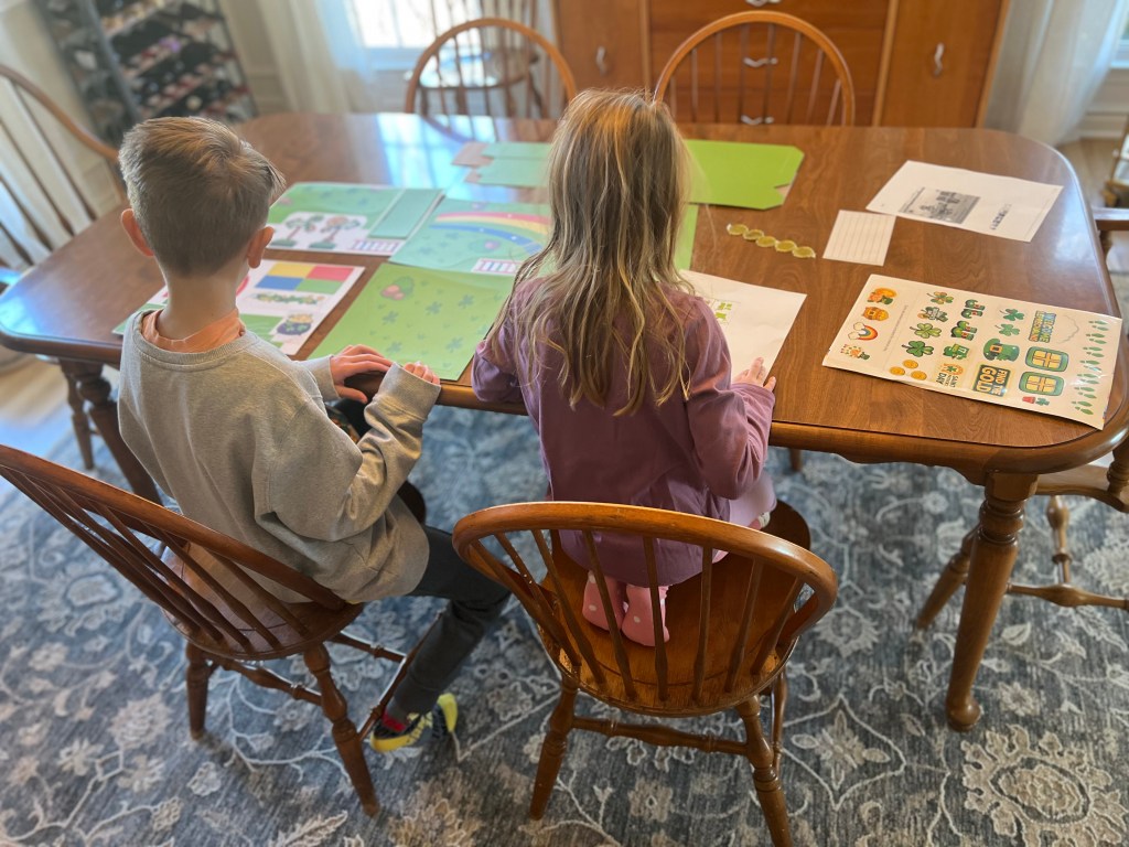 Kids sitting at a table starting to build a leprechaun trap for a St. Patrick’s Day craft activity