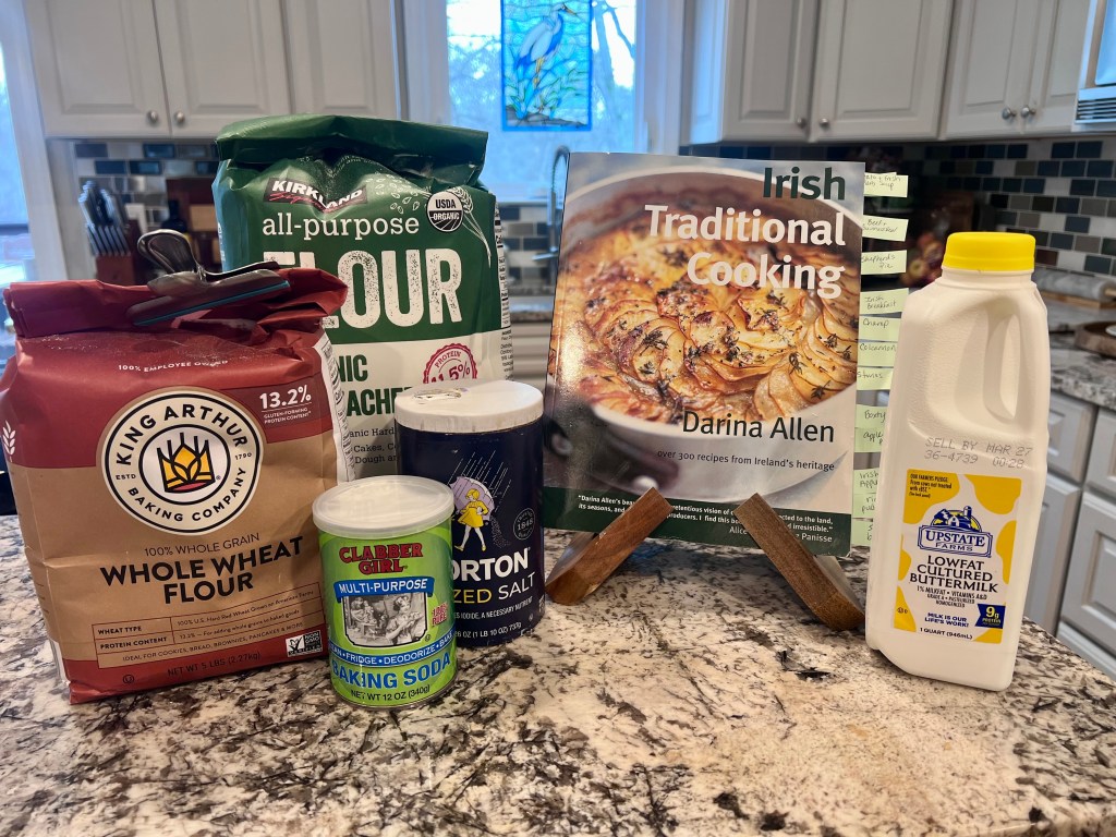 Irish soda bread ingredients on a kitchen counter with Irish Traditional Cooking cookbook by Darina Allen before baking