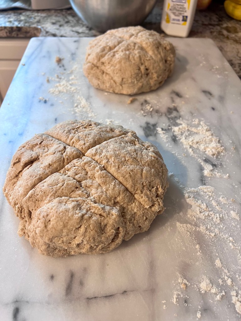 Irish soda bread dough shaped and scored on a pastry slab before baking