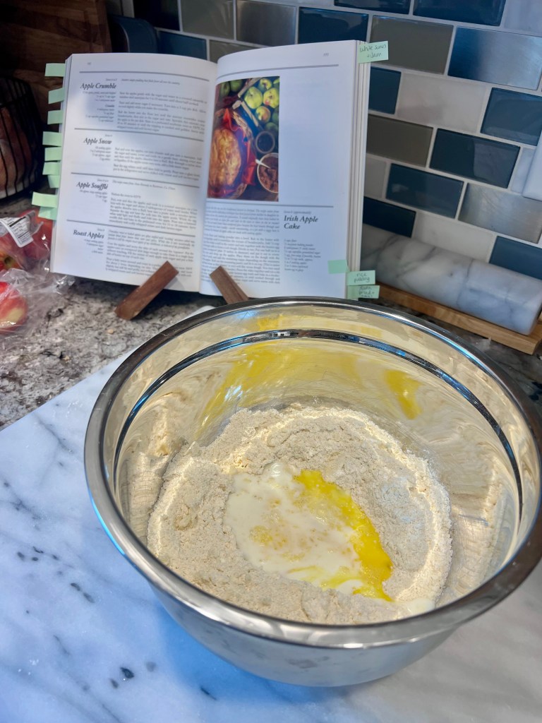 Preparing Irish apple cake dough with dry ingredients and wet ingredients in a well before mixing