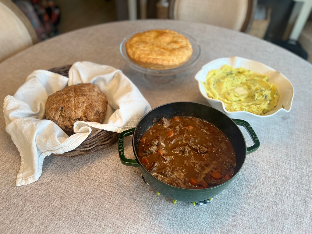 Irish St. Patrick’s Day dinner spread with beef stew, champ, apple cake, and soda bread on the table