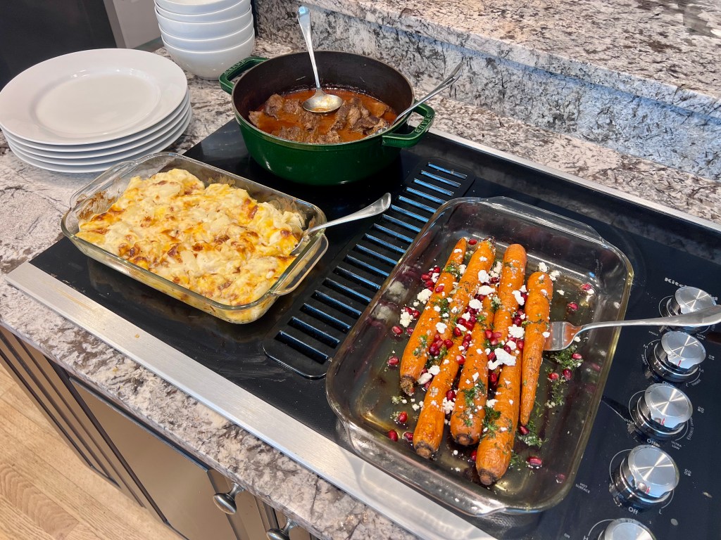 Easter meal on the counter with honey roasted carrots, Barolo braised beef, and scalloped potatoes ready to serve