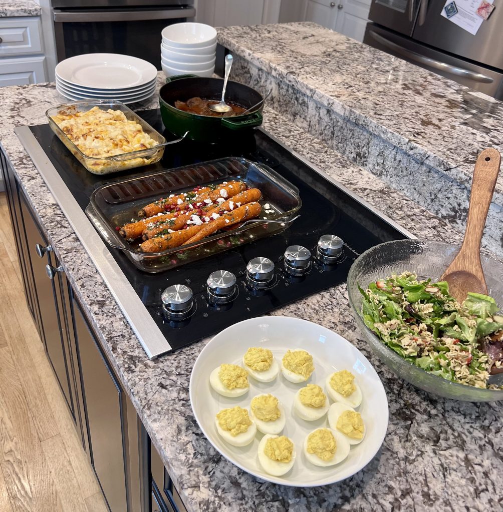 Easter dinner spread with strawberry salad, braised beef, scalloped potatoes, and roasted carrots on the counter